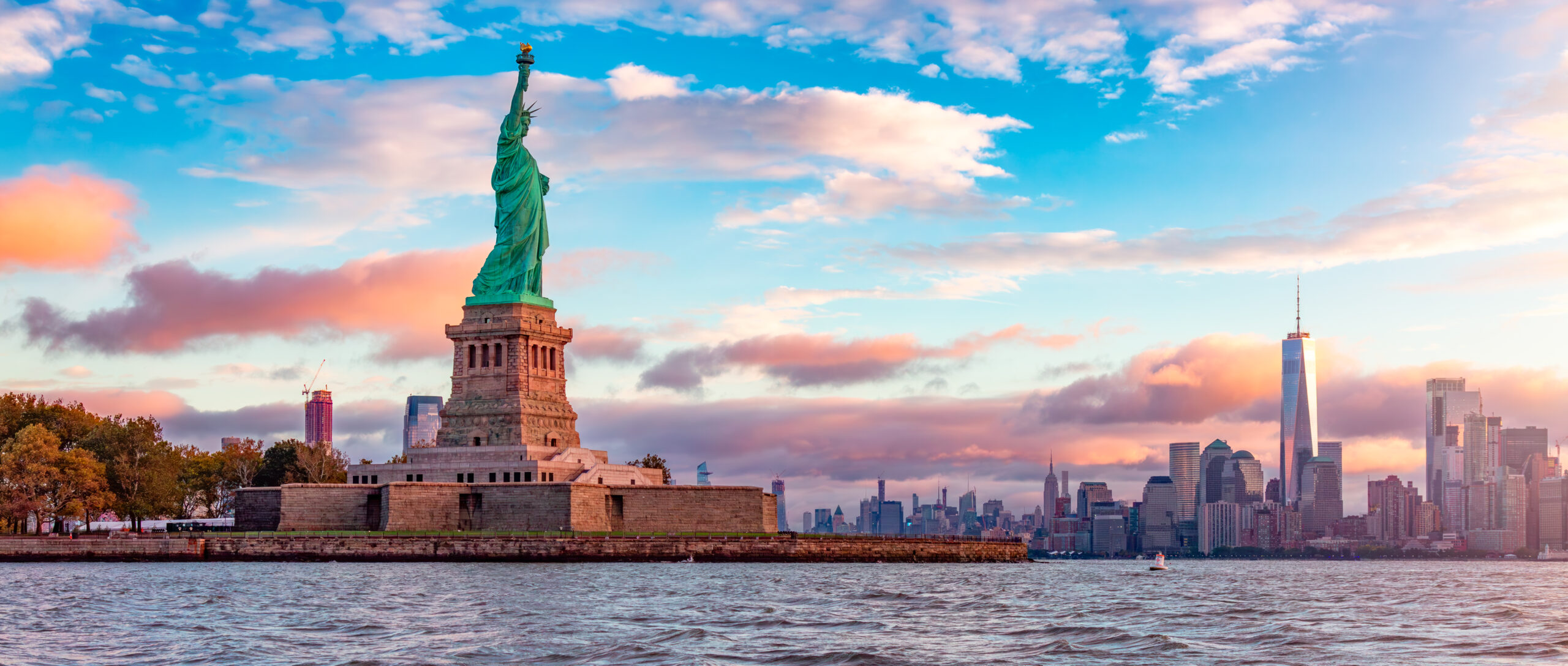 Statue of Liberty and Downtown Manhattan in the background. Vibrant cloudy sunrise. Jersey City, New Jersey, United States.