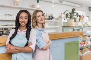 young attractive multiethnic waitresses looking at camera while standing together with arms crossed